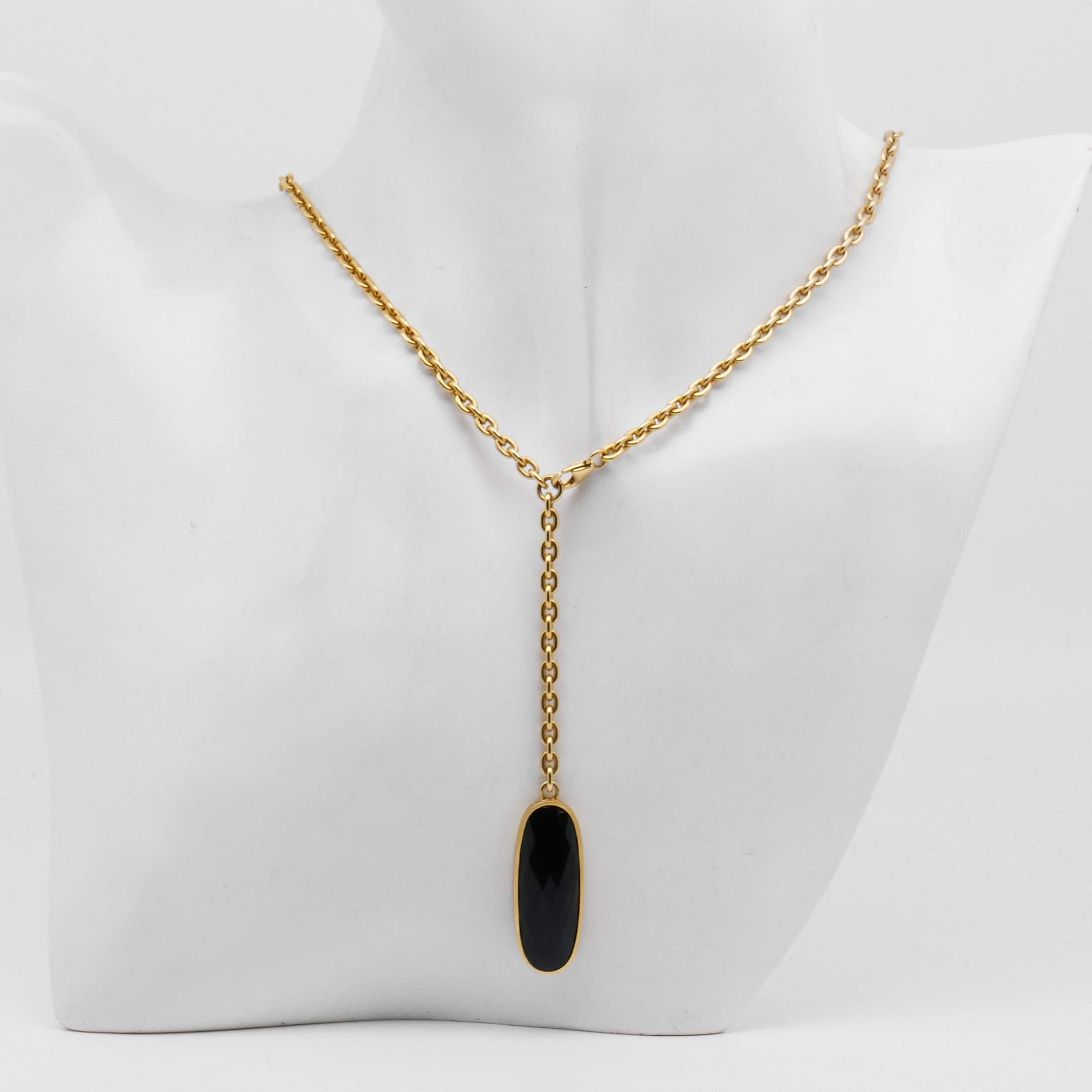 Collier von Toni Gard aus 585 Gelbgold mit dunkel facettiertem länglichem Anhänger an einer weißen Schmuckbüste