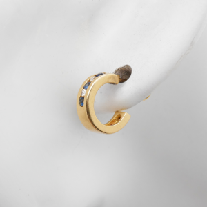 Goldener Ohrstecker mit Diamanten und blauen Saphiren am Ohrdisplay