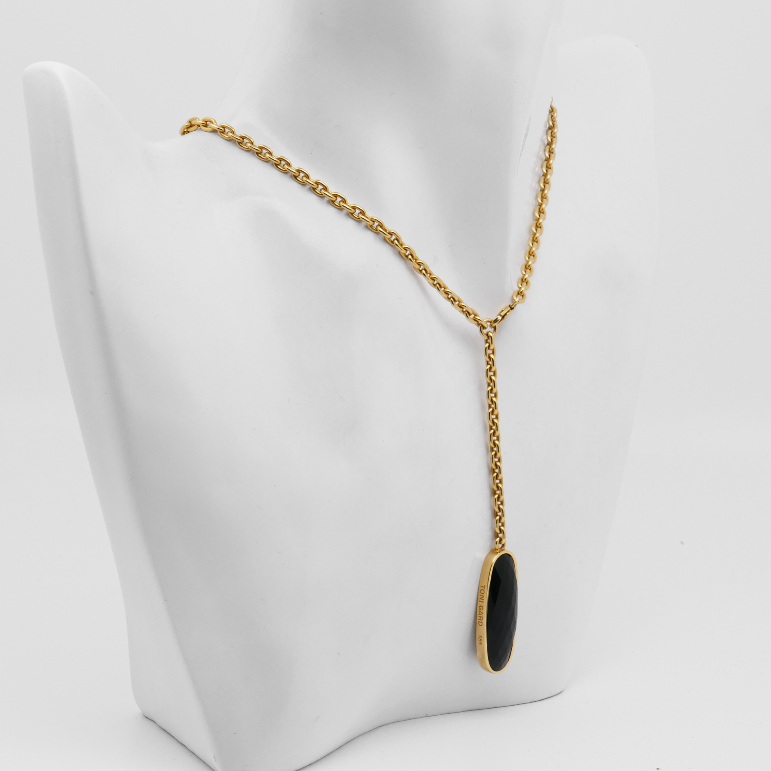 Schräg fotografiertes 585 Gelbgold Collier von Toni Gard mit dunkel facettiertem Anhänger