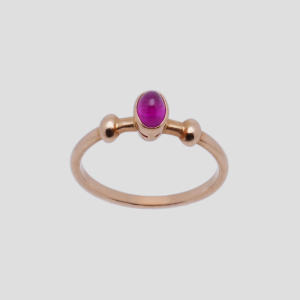 Freigestellter Ring aus 583 Roségold mit rotem Cabochonstein vor hellem Hintergrund