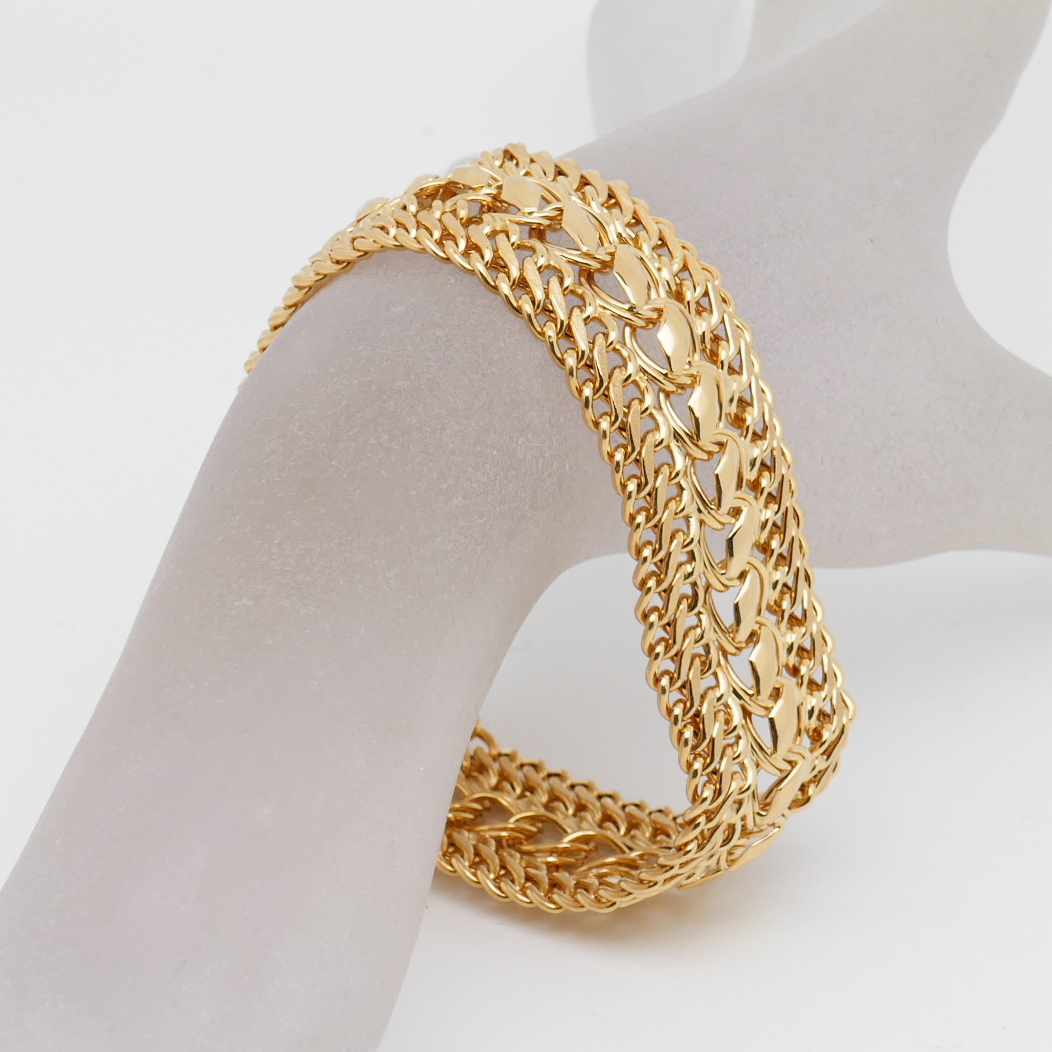 Nahaufnahme eines massiven Goldarmbands mit dekorativer Mittelstruktur und Panzerketten-Design